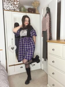 Our stylish influencer Amy in a purple and black plaid dress and black combat boots, ready for a concert.